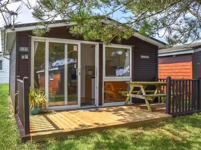 a screened in porch of a tiny house with a picnic table at Harbour Cove - Uk47722 in St Merryn