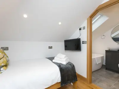 a bedroom with a bed and a tub and a tv at Nova Cottage in St Ives
