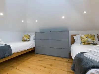 a bedroom with two beds and a dresser at Nova Cottage in St Ives