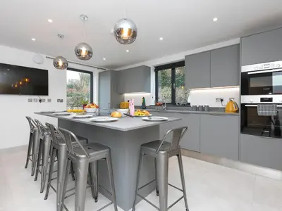 a kitchen with a large gray island with bar stools at Nova Cottage in St Ives