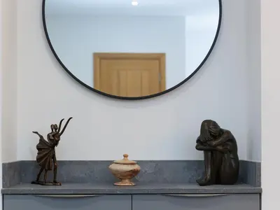 a mirror on a wall above a table with statues at Avon Cottage in St Ives