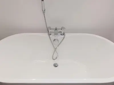 a bathtub with a shower head hanging from a ceiling at Avon Cottage in St Ives