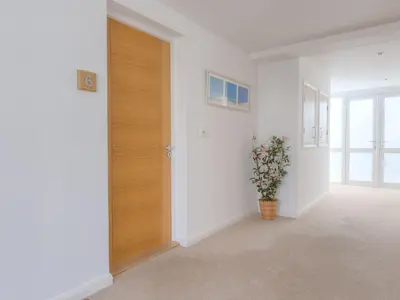a hallway with a door and a vase of flowers at Sea Bleu in St Ives