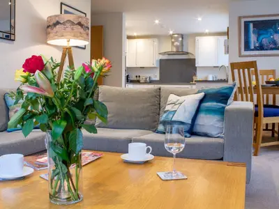 a living room with a couch and a table with flowers at Sea Bleu in St Ives