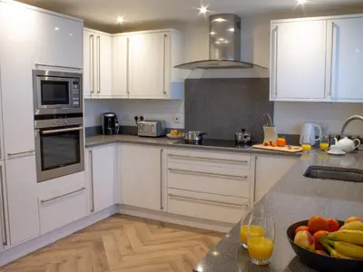 a kitchen with white cabinets and a bowl of fruit on the counter at Sea Bleu in St Ives