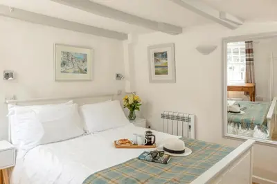 a white bed with a tray of food on it at Castle Cottage, Port Isaac Bay Holidays in Port Isaac