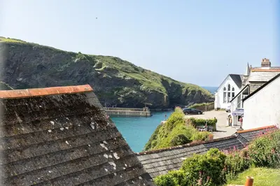 a view of a body of water with a mountain at Castle Cottage, Port Isaac Bay Holidays in Port Isaac