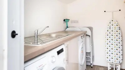 a kitchen with a sink and a washing machine at Castle Cottage, Port Isaac Bay Holidays in Port Isaac