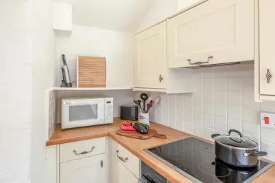 a kitchen with white cabinets and a microwave at Castle Cottage, Port Isaac Bay Holidays in Port Isaac