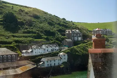 a village on a hill with houses and a lighthouse at Castle Cottage, Port Isaac Bay Holidays in Port Isaac