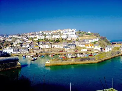 a town on a hill next to a body of water at The Coach House in Par
