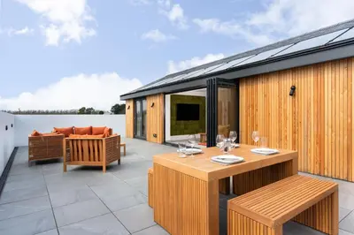 an outdoor patio with a table and chairs at Brand new, Gwithian lodge, eco home in Praze an Beeble