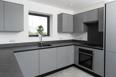a kitchen with white cabinets and a sink and a window at Brand new, Gwithian lodge, eco home in Praze an Beeble