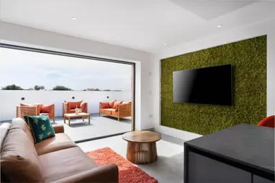 a living room with a couch and a flat screen tv at Brand new, Gwithian lodge, eco home in Praze an Beeble