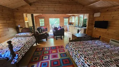a bedroom with two beds in a log cabin at Roseland Valley Retreat in Tregoney