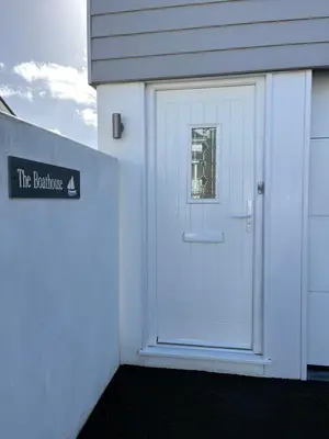 a white door with a sign on the side of a building at The Boathouse in Mylor Bridge