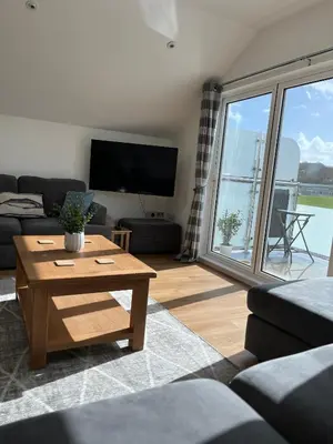 a living room with a table and a large window at The Boathouse in Mylor Bridge