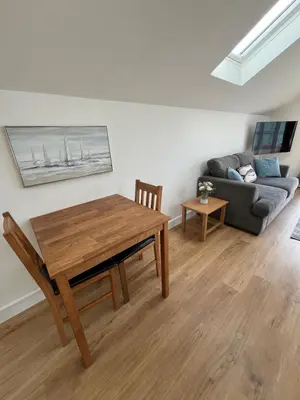 a living room with a wooden table and a couch at The Boathouse in Mylor Bridge