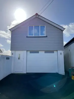 a garage with two white doors and a window at The Boathouse in Mylor Bridge