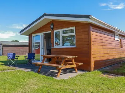 a tiny house with a picnic table and chairs at Cornish Holiday at Atlantic Bays in St Merryn