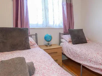 a bedroom with two beds and a wooden table at Cornish Holiday at Atlantic Bays in St Merryn