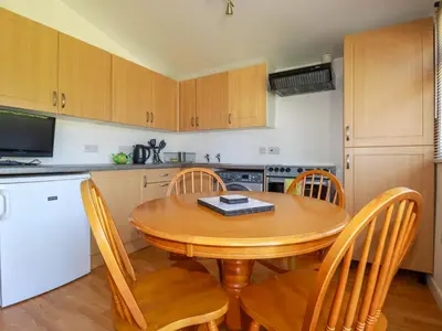 a small kitchen with a wooden table and chairs at Cornish Holiday at Atlantic Bays in St Merryn