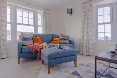 a blue couch in a living room with windows at Sandpipers, Port Isaac Bay Holidays in Port Isaac