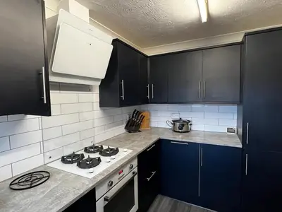 a kitchen with black cabinets and a white stove top oven at Cornish Highbury in Hayle