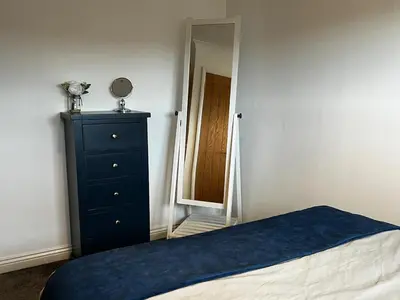 a bedroom with a blue dresser and a mirror at Cornish Highbury in Hayle