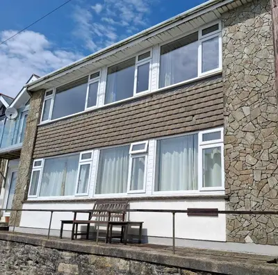 a building with two chairs sitting outside of it at Loe Bar Top in Porthleven