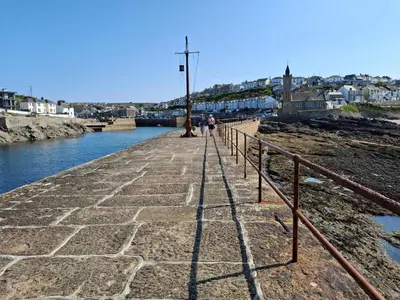 a group of people walking on a pier next to a river at Loe Bar Top in Porthleven