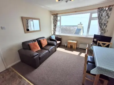 a living room with a leather couch and a table at Loe Bar Top in Porthleven