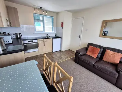 a living room with a couch and a kitchen at Loe Bar Top in Porthleven