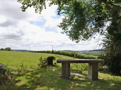 a wooden bench sitting in the middle of a field at Nuthatch by Together Travel - Luxury Cornish Countryside Retreat in Bodmin