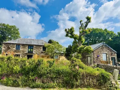 an old stone house in a field of flowers at Nuthatch by Together Travel - Luxury Cornish Countryside Retreat in Bodmin