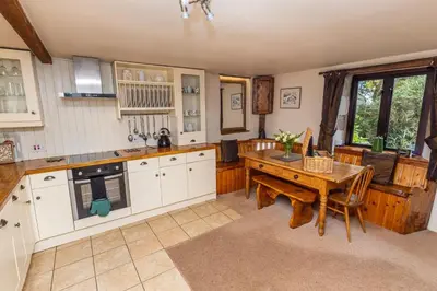 a kitchen with white cabinets and a wooden table at Tawnawood by Together Travel - Luxury Cornish Countryside Retreat in Bodmin