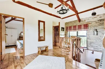 a living room with a stone wall and wooden beams at Tawnawood by Together Travel - Luxury Cornish Countryside Retreat in Bodmin