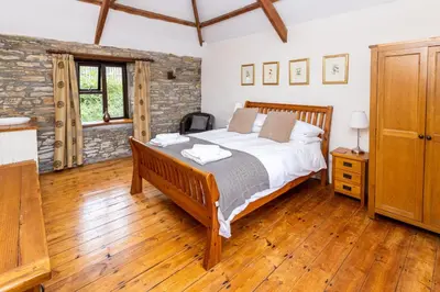 a bedroom with a bed and a wooden floor at Tawnawood by Together Travel - Luxury Cornish Countryside Retreat in Bodmin