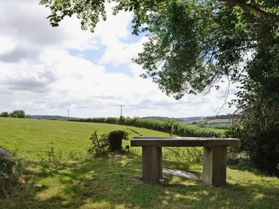 a wooden bench sitting in the middle of a field at Tawnawood by Together Travel - Luxury Cornish Countryside Retreat in Bodmin