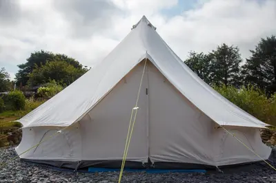 a white tent is set up on the rocks at Glamping Meadow Bell Tent in Stithians