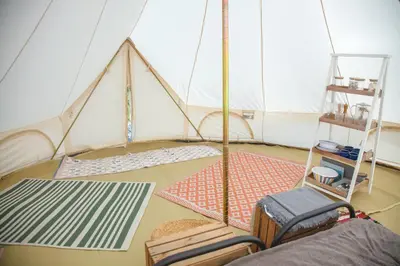 a room with a tent with mats and chairs at Glamping Meadow Bell Tent in Stithians