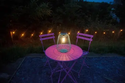 a pink table and two chairs with a candle on it at Glamping Meadow Bell Tent in Stithians