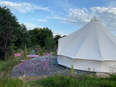 a white tent with two chairs and a table at Glamping Meadow Bell Tent in Stithians