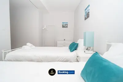two beds in a white room with blue pillows at Spacious 2 Bedroom Flat By LS2G Short Lets & Serviced Accommodation Greater London With Free WIFI in Newquay