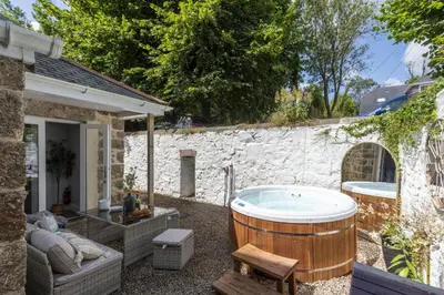 a hot tub in a yard next to a stone wall at The Elms in Uny Lelant