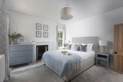a white bedroom with a bed and a fireplace at The Elms in Uny Lelant