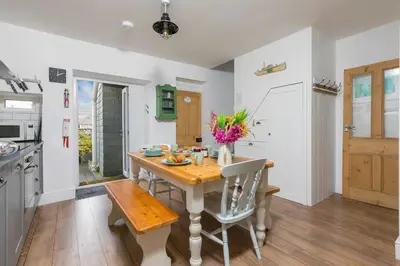 a kitchen with a wooden table with flowers on it at Benjamin's Bolthole in St Ives
