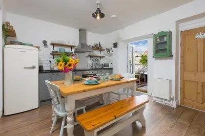 a kitchen with a wooden table and a white refrigerator at Benjamin's Bolthole in St Ives