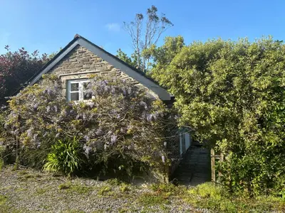 a house with a hedge of purple flowers at Wisteria Cottage in Truro