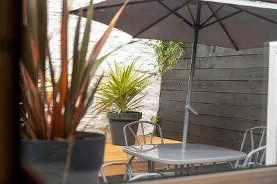 a table and chairs with an umbrella on a patio at The Flat - Brand new renovation in amazing location in St. Agnes